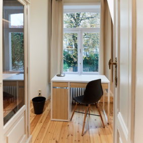 furnished bedroom with design desk and wooden floor