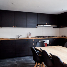 fully equipped kitchen designed in black with a big dining table in a shared house for expats in Brussels