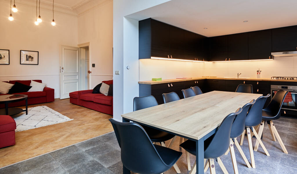 fully equipped kitchen designed in black with a big dining table in a shared house for expats in Brussels