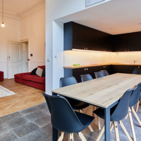 fully equipped kitchen designed in black with a big dining table in a shared house for expats in Brussels