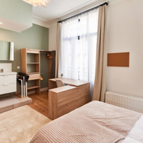 room with a comfortable double bed and private shower in a coliving in Brussels close to different points of interest