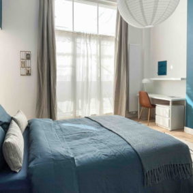 Spacious blue bedroom with double bed and private balcony and walk in closet in a shared house near the EU quarter